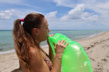 women inflates swimming ring donut on the seashore