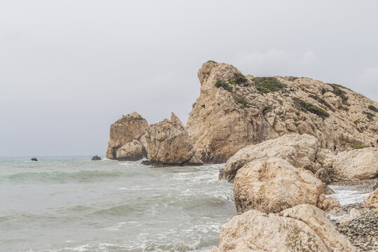 View of Aphrodite's Rock rising majestically from the turquoise waters, its rugged, sun-kissed facade carved by time and tide, Paphos, Cyprus.