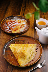 Delicious crepes served on wooden table with tea