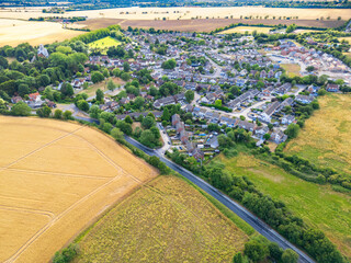 Aerial view of a typical British village seen within arable farm fields in Essex. The road on the lower right feeds to the village community. Seen during a drought in Summer.