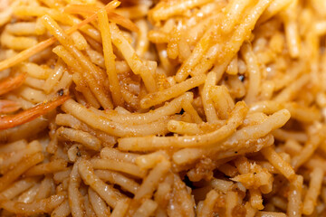 Primer plano de fideos tostados en fideuá tradicional española. / Close-up of toasted noodles in traditional Spanish fideuá.