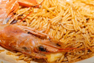 Plato de fideuá con fideos tostados y gambas frescas. / Fideuá dish with toasted noodles and fresh prawns.