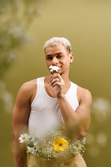 Charming young man with dyed hair enjoys flowers in a vibrant studio setting