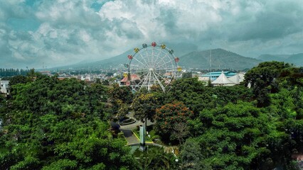Beautiful aerial view of the Ferris wheel and playground in the middle of lush green natural park