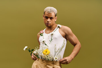 Young man showcases floral style in trendy tank top within vibrant studio setting