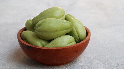 Baby chayote (labu siam) on wooden bowl with greybackground