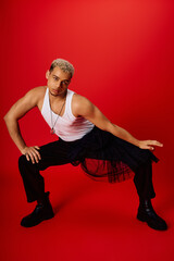 Confident young man showcases trendy fashion in vibrant red studio backdrop