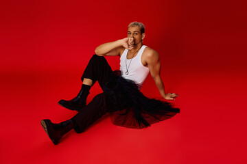 Stylish young man expresses confidence in vibrant red studio setting