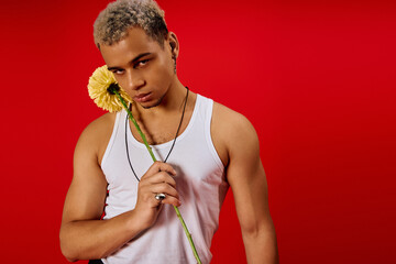 Striking young man showcases fashion style in vibrant red studio setting
