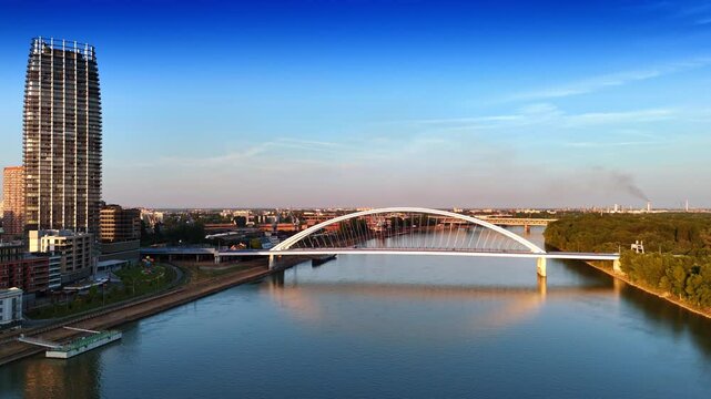 Cars run by the beautiful Appolo Bridge over the Danube River. Sunset in Bratislava, Slovakia. Aerial view.