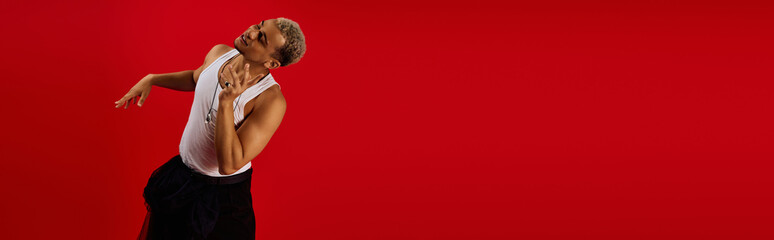 Young African American man showcases trendy style in vibrant red studio setting