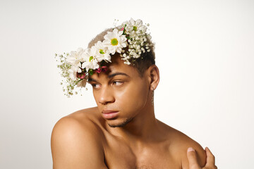 Young muscular man with dyed hair and flower crown posing in studio setting