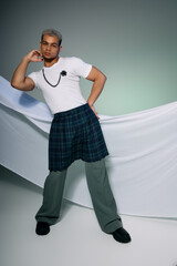 Stylish young man with dyed hair showcasing diverse fashion in studio setting