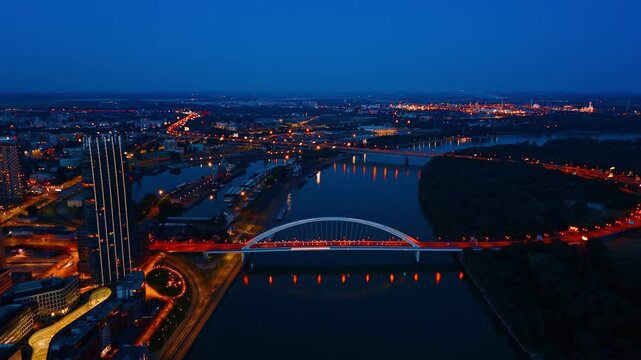 Beautifully illuminated roads of Bratislava, Slovakia. Drone flight approaching the Appolo Bridge over the Danube at night.