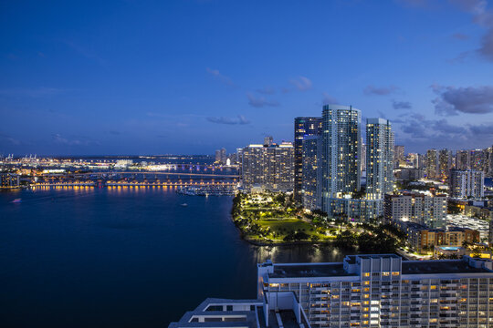 Aerial view of the vibrant city lights mirroring on the tranquil waters, illuminating the skyline with the Julia Tuttle Causeway in the distance, Miami, Florida, United States.