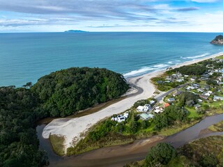 Aerial view of a river flowing into the ocean at a beach in Whiritoa, New Zealand. The river...