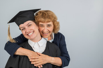 Portrait of Caucasian woman in graduation gown with her mother. 