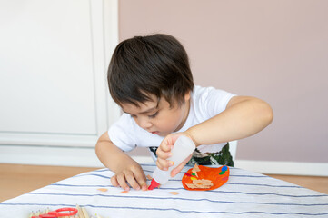 ittle boy doing craft activity at home, child using glue for art project,Kid using colour paper...