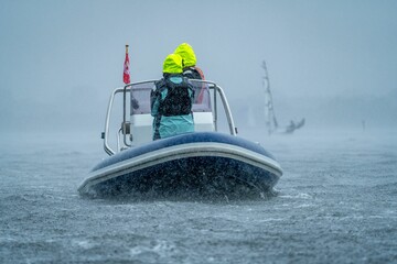 Navigating a motorboat through rainy waters.