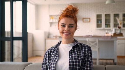 Smiling positive satisfied Caucasian woman cheerful female carefree girl at home couch relaxing looking at camera resting in living room enjoying tenant own apartment loan mortgage smile insurance