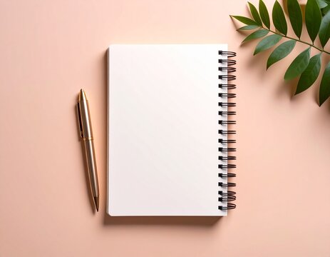 A blank notebook and pen rest on a pastel pink surface, with a leafy branch.