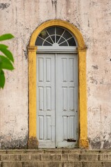 Single gray paneled door stands beneath a half-moon transom window.