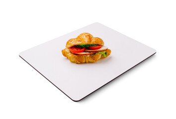 Delicious croissant sandwich with fresh ingredients on a white surface