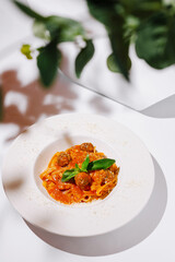 Delicious meatball pasta served in a white bowl with fresh herbs