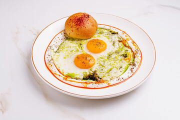 Brightly colored eggs served on a plate with bread and sauce