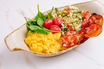 Delicious breakfast bowl featuring scrambled eggs, greens, and crispy bacon