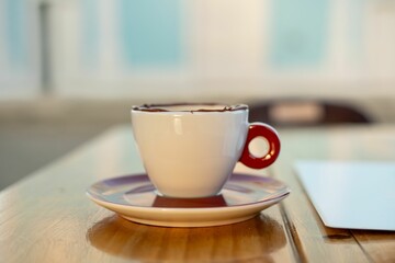 White coffee cup with red handle in a cafe.