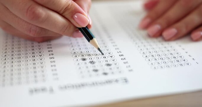 Female fills out multiple-choice test sheet using pencil. Woman hands darken answer bubbles with careful deliberate pencil strokes slow motion