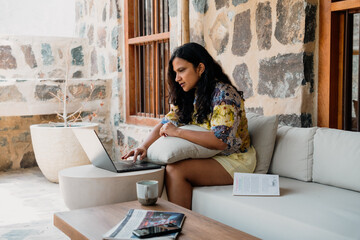 woman working remotely in a beach retreat she is typing in laptop and attending skype meetings