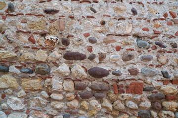 An old stone wall made of pebbles and bricks. Texture. Architecture.