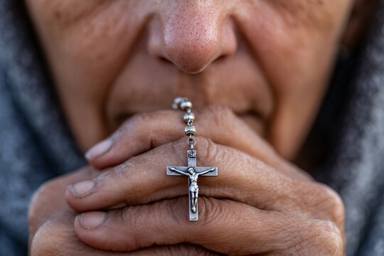 elderly woman praying with crucifix rosary showing devotion and faith in jesus