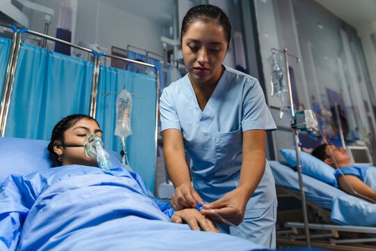 Nurse attending to a patient with an air mask in a hospital setting