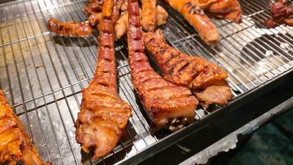 Close-up of crispy pork tails grilled to perfection, displayed on a wire rack at a street food vendor’s stall
