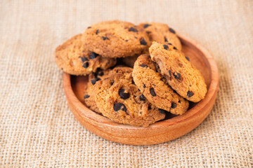 chocolate chip cookies in a wooden plate on burlap