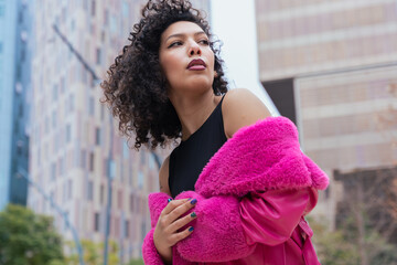 African american dancer with curly hair wearing a pink coat, expressing movement and energy in an...