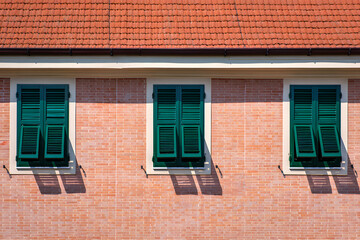 Fototapeta premium Three Dark Green Shutters on a Brick Wall, Mediterranean Style, Sunny Day
