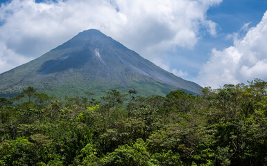 Arenal volcano emerging from the forest under cloudy sky. Costa Rica national park