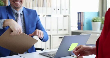 Woman in red dress handshakes with man and signs document presented on clipboard. Act of agreement at desk in modern business setting slow motion