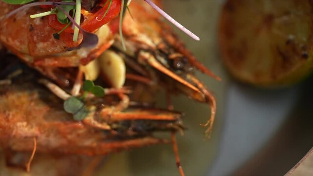 A plate of shrimp with green herbs on top. The shrimp are cooked and appear to be seasoned well. The herbs add a fresh and healthy touch to the dish