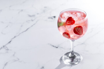 Strawberry gin tonic cocktail on white marble background. Copy space