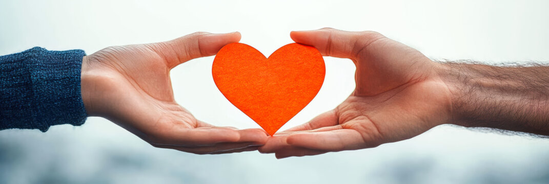 Close-up of two hands holding bright red paper heart together symbolizing love relationship connection and unity on blurred background