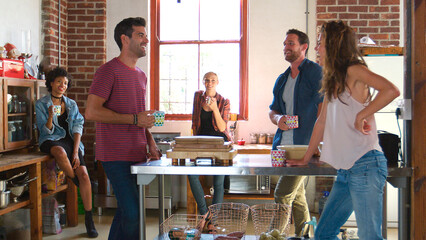Group Of Young Friends Meeting For Coffee In Loft Apartment