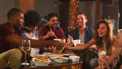Group Of Young Friends Sharing Chinese Takeaway Meal In Loft Apartment