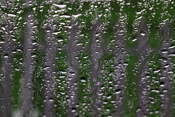 Rain drops on the window glass infront of a fence