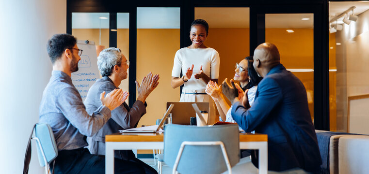 Diverse team applauding a young speaker during a meeting in a bright office