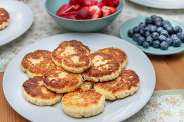 Syrniki or fried cottage cheese pancakes on white plate on the table.